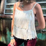 A woman wearing the Cream Fringe Faux Suede Cami with wine bell bottoms.
