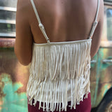 A woman wearing the Cream Fringe Faux Suede Cami with wine bell bottoms.