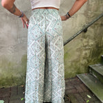A woman wearing the Sage Linen Pants with Front Slit and a white bralette.