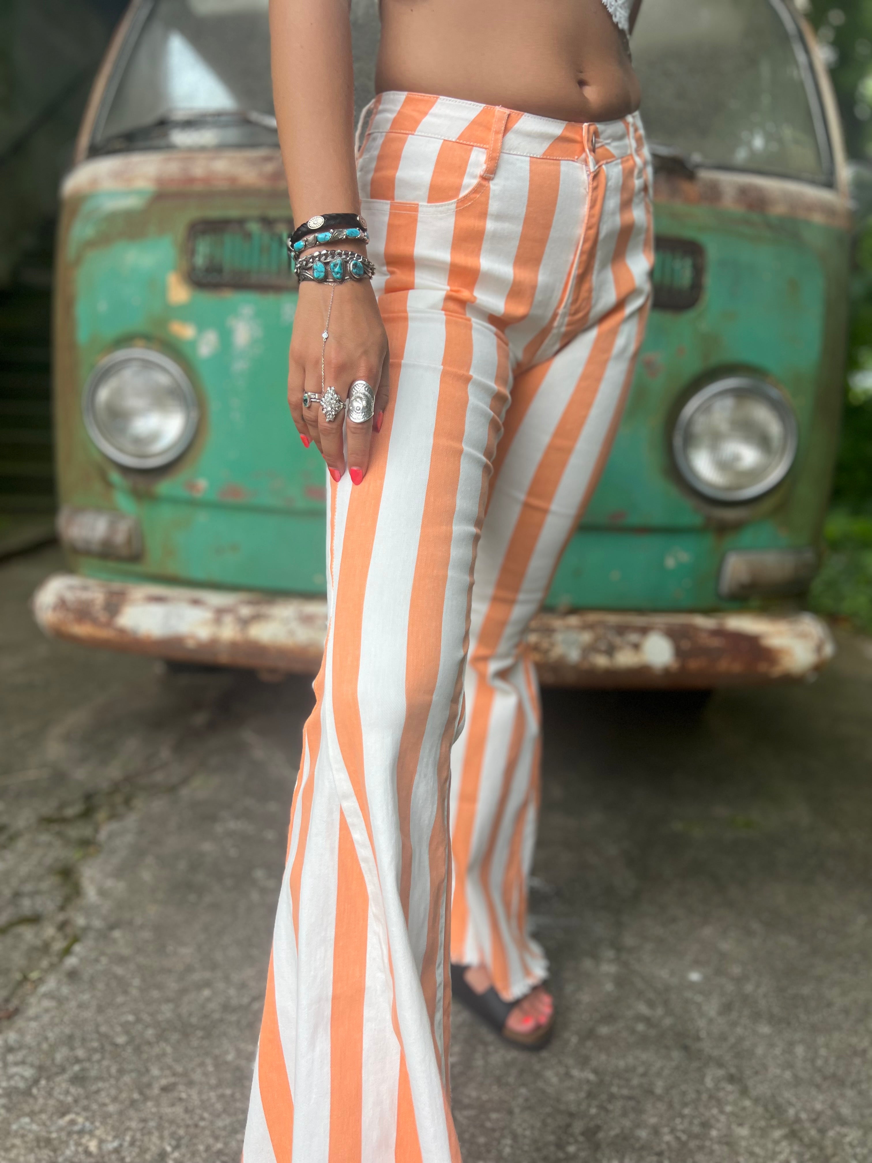 A woman wearing the Papaya Striped Washed Denim Bell Bottoms and a white bralette.