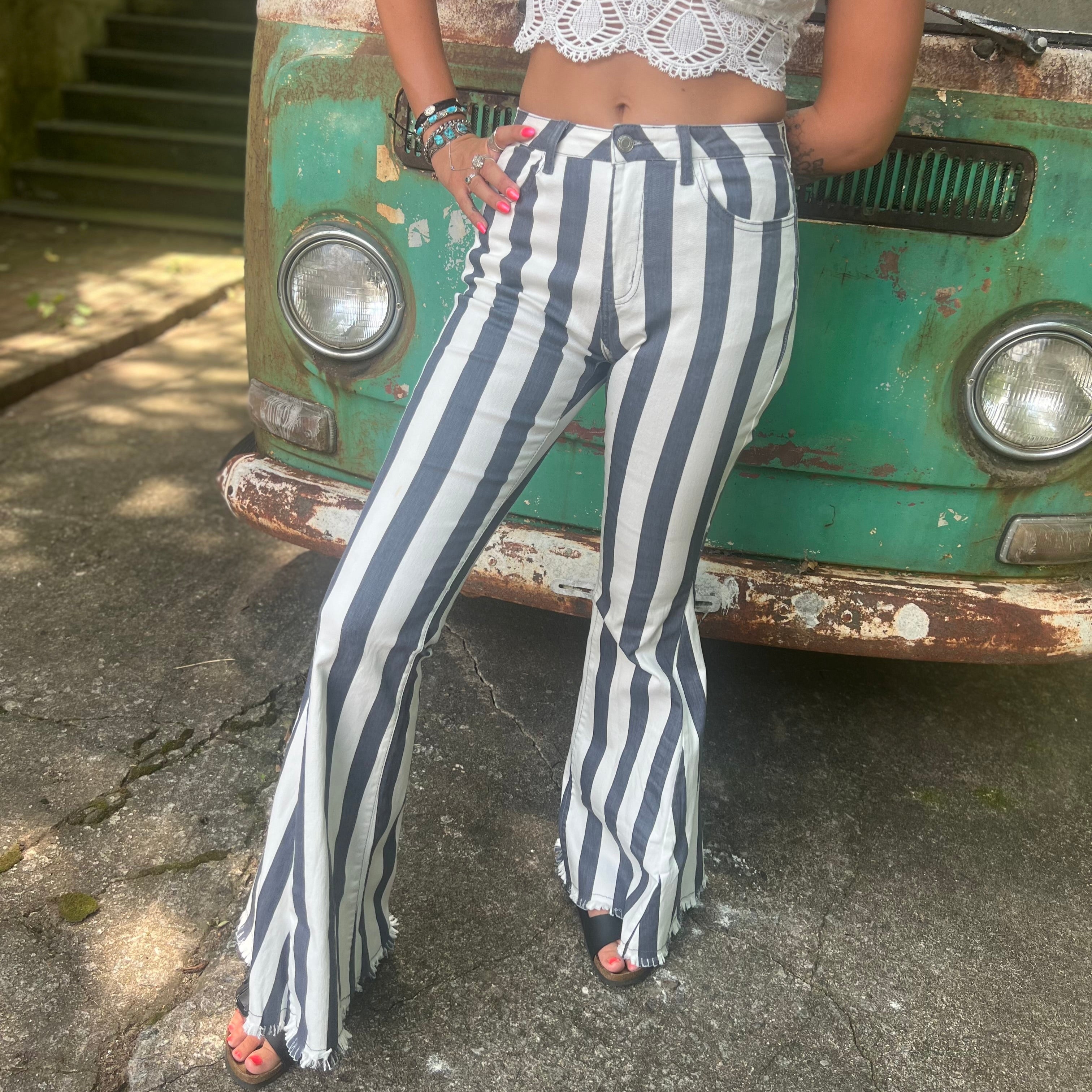 A woman wearing the Cream and Grey Striped Distressed Denim Bell Bottoms and a white bralette.