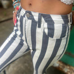 A woman wearing the Cream and Grey Striped Distressed Denim Bell Bottoms and a white bralette.
