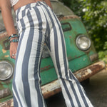 A woman wearing the Cream and Grey Striped Distressed Denim Bell Bottoms and a white bralette.