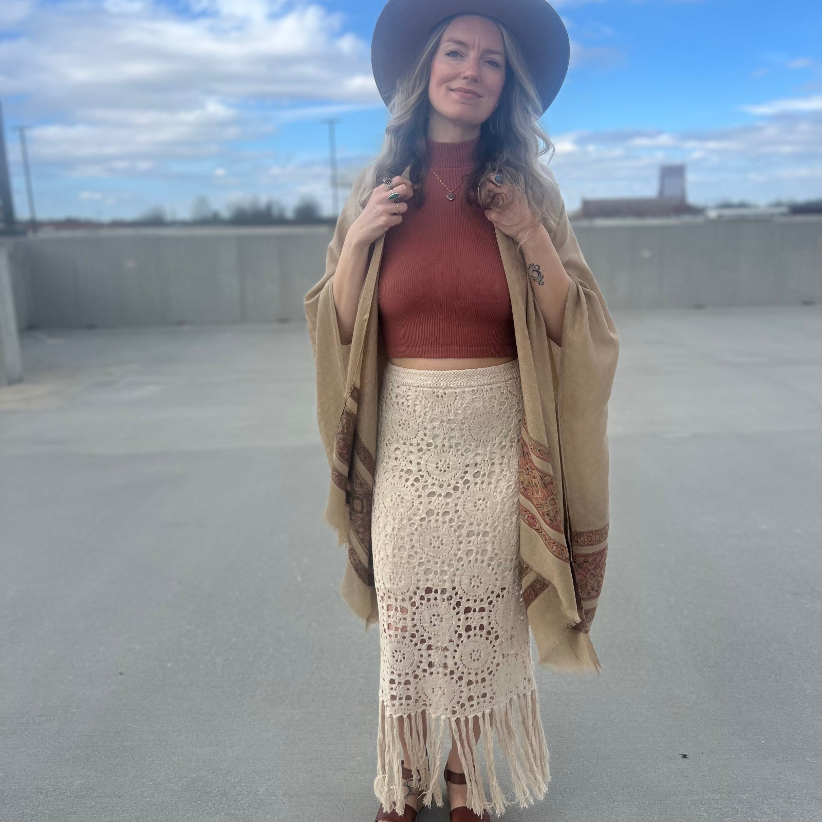 A woman wearing the Crochet-Knit Lace Fringe Maxi Skirt with a red top and a kimono.