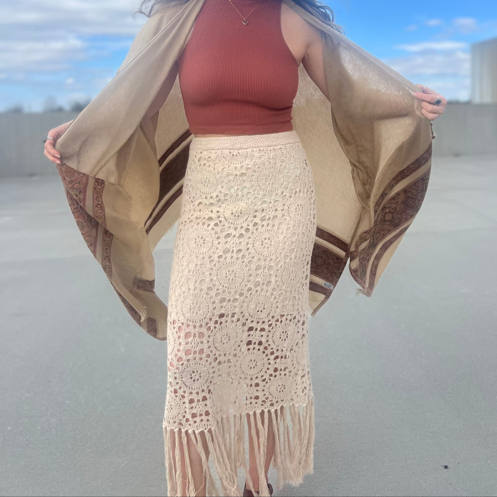 A woman wearing the Crochet-Knit Lace Fringe Maxi Skirt with a red top and a kimono.
