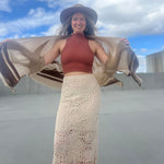 A woman wearing the Crochet-Knit Lace Fringe Maxi Skirt with a red top and a kimono.