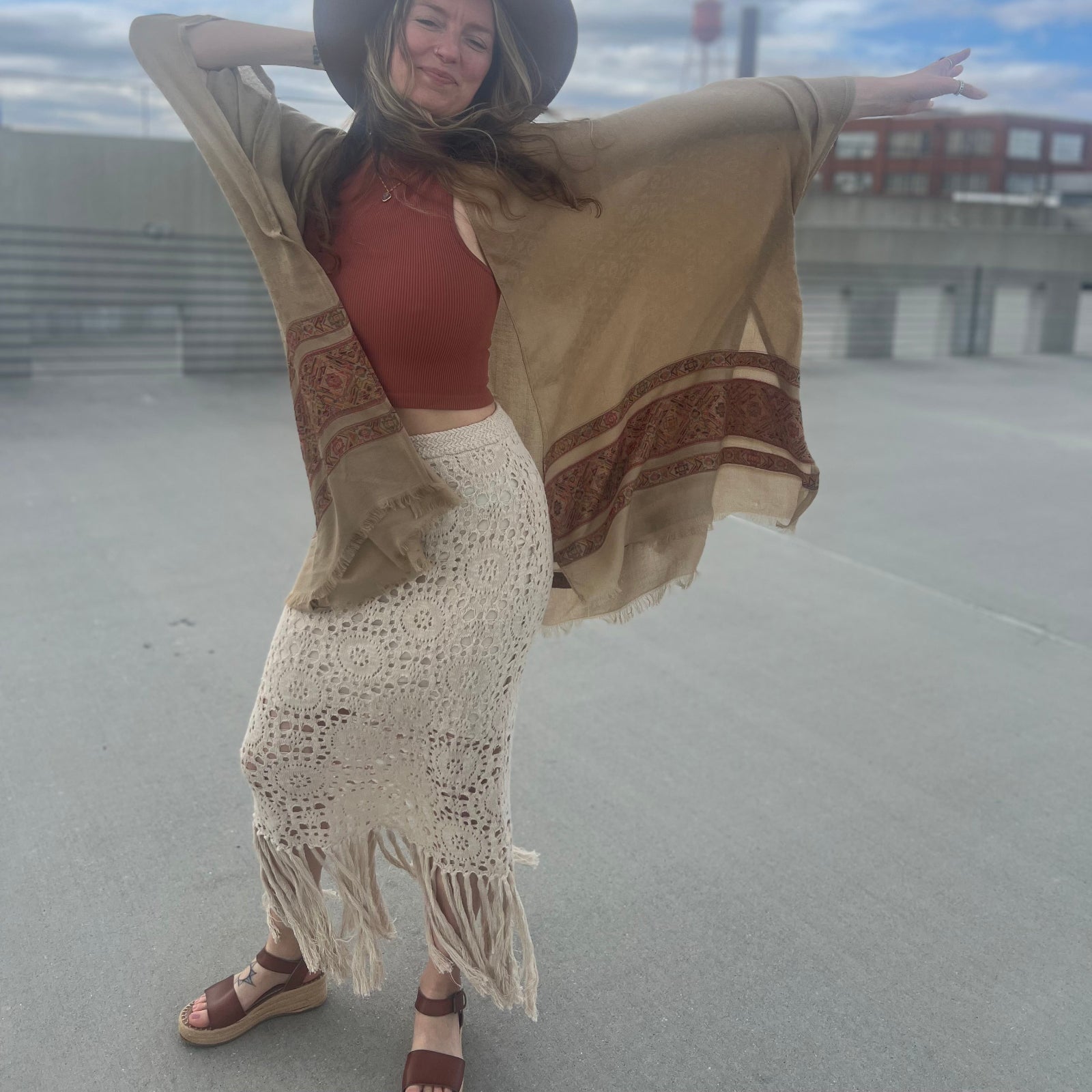A woman wearing the Crochet-Knit Lace Fringe Maxi Skirt with a red top and a kimono.