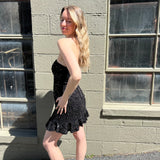 A woman wearing the espresso Sequin Lace-Up Back Strapless Mini Dress.