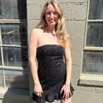 A woman wearing the espresso Sequin Lace-Up Back Strapless Mini Dress.