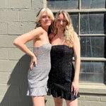 Two women wearing the espresso and black Sequin Lace-Up Back Strapless Mini Dresses.