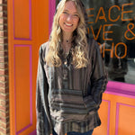 A woman wearing the agate Womens Half Button Baja Hoodie with jeans in front of a pink and orange wall.