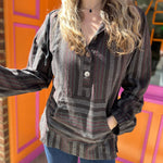 A woman wearing the charcoal Womens Half Button Baja Hoodie with jeans in front of a pink and orange wall.