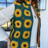 A woman wearing the Sunflower Flower Granny Square Fleece Lined Wool Vest with a white sweater and jeans.