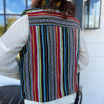 A woman wearing the Sunflower Flower Granny Square Fleece Lined Wool Vest with a white sweater and jeans, showing off the back.