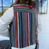 A woman wearing the Sunflower Flower Granny Square Fleece Lined Wool Vest with a white sweater and jeans, showing off the back.