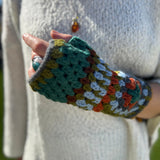 Someone wearing the Turquoise Granny Square Pure Wool Fingerless Mitten Gloves for Women.