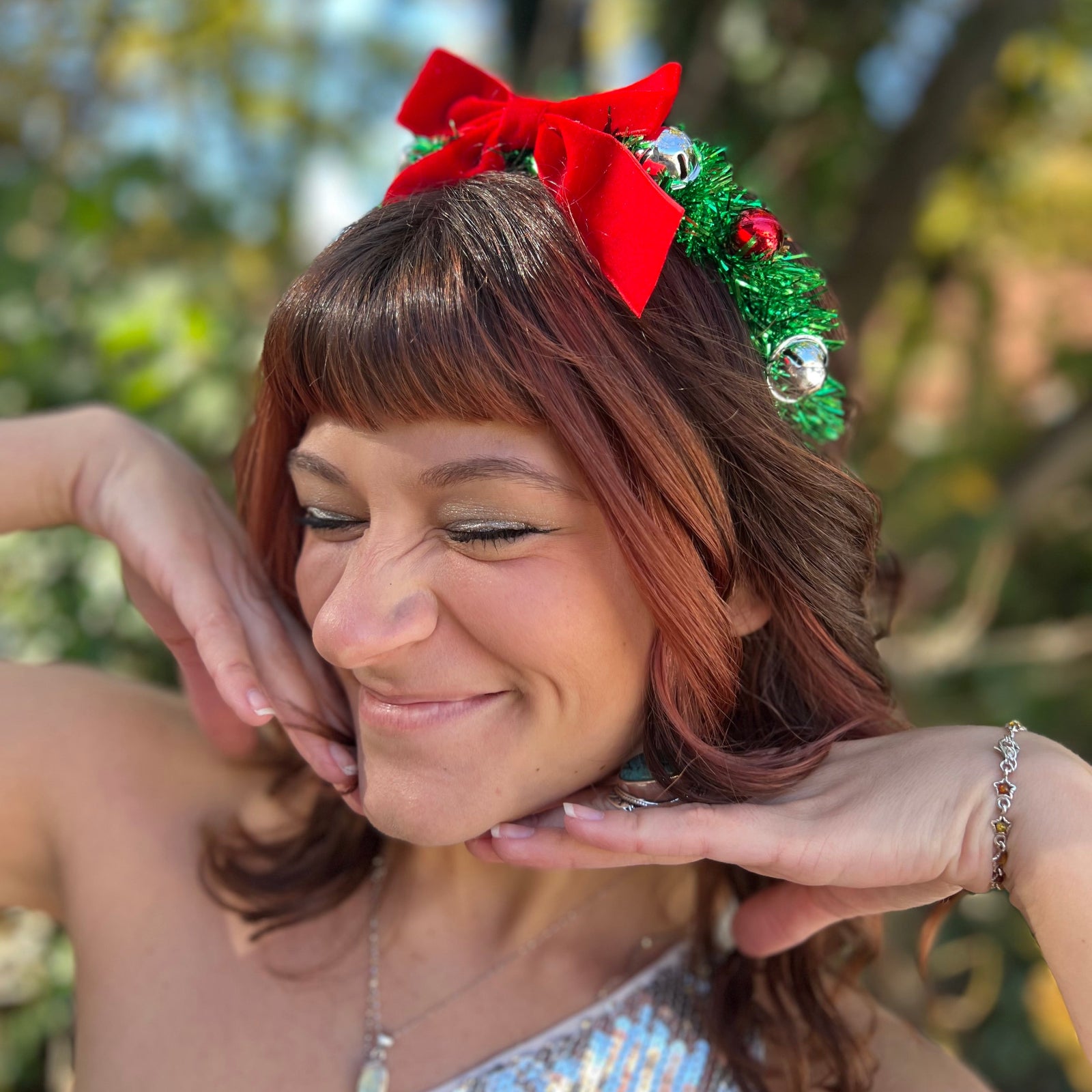 A woman wearing the Oh Christmas Fringe & Bow Headband with a silver dress.