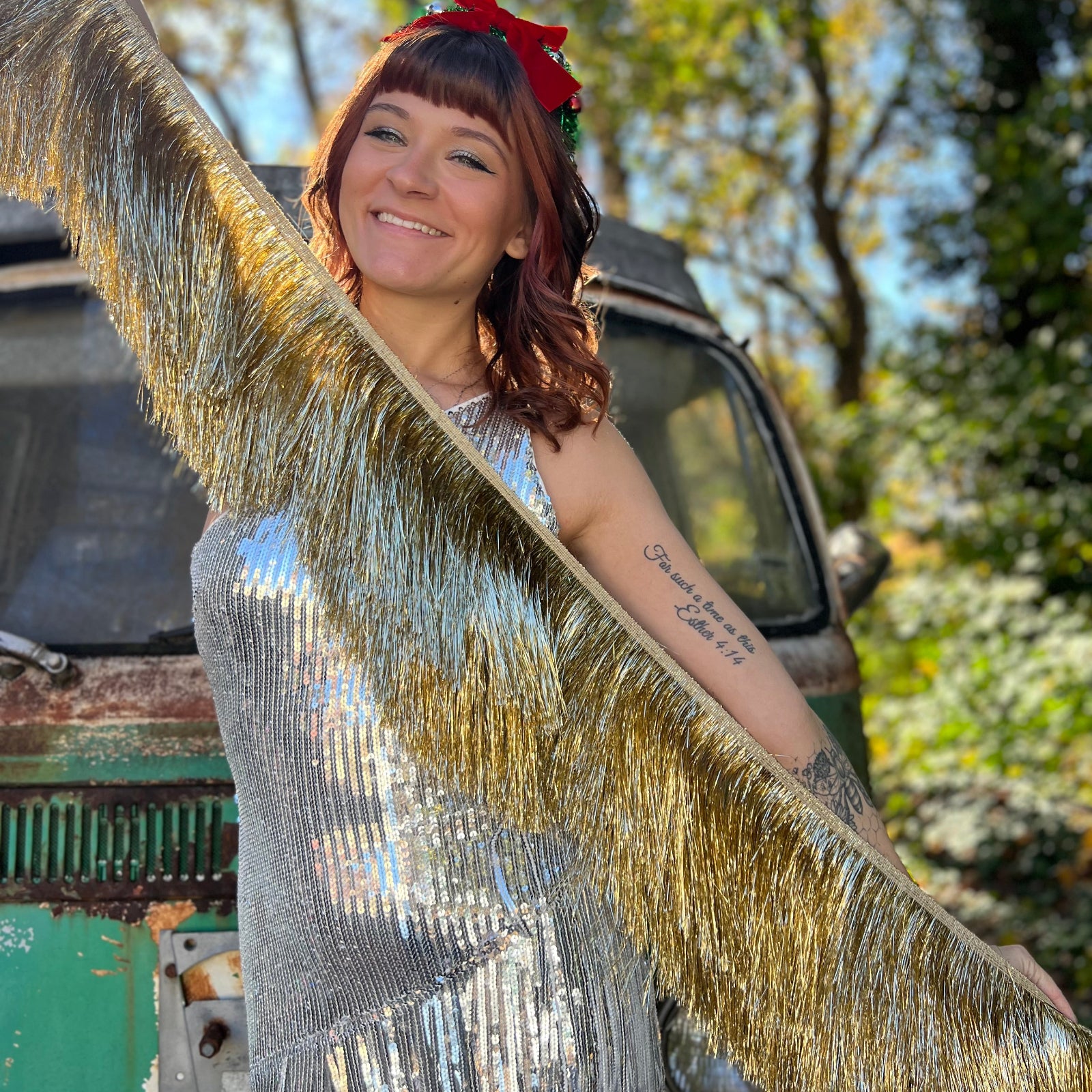 A woman holding the Stay Golden Scalloped Fringe Banner in front of a teal vintage Volkswagen bus.
