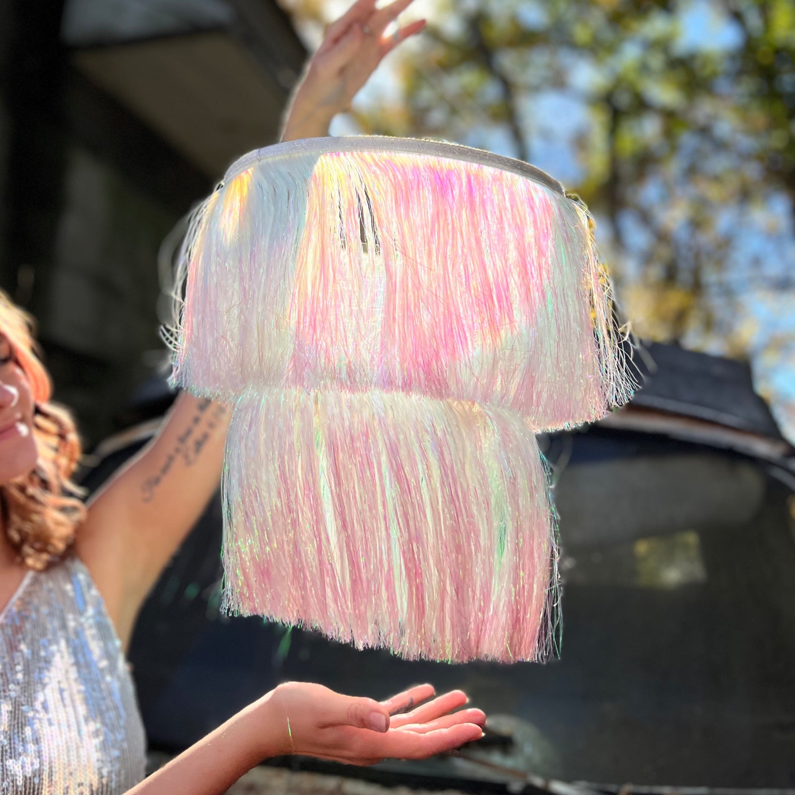A woman in a silver dress holding the Iridescent Fringe Party Chandelier.