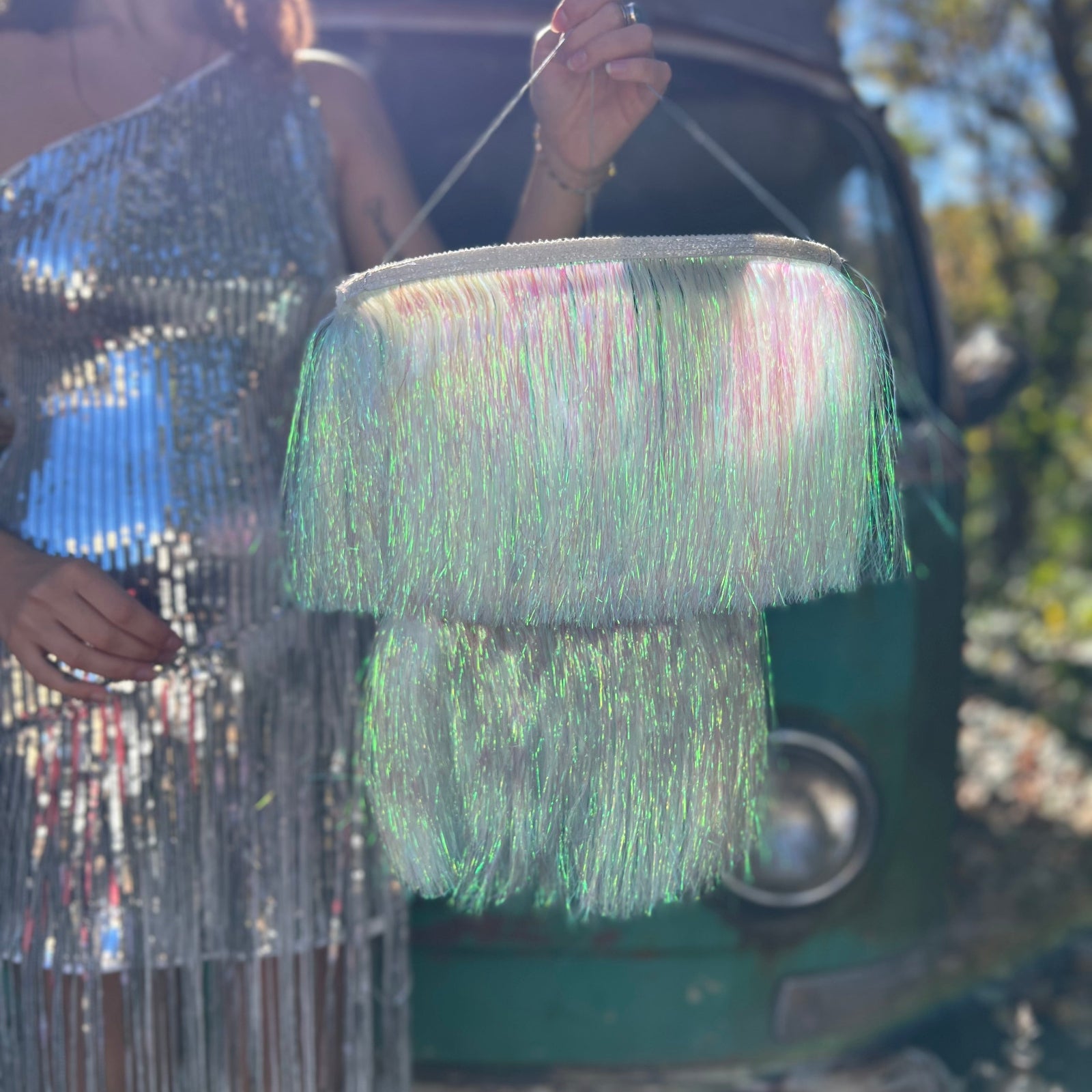 A woman in a silver dress holding the Iridescent Fringe Party Chandelier.