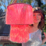 A woman holding the Iridescent Pink Fringe Party Chandelier in front of herself.
