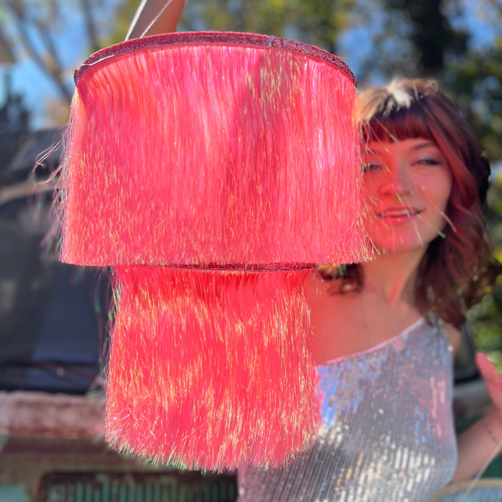 A woman holding the Iridescent Pink Fringe Party Chandelier in front of herself.