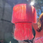 A woman holding the Iridescent Pink Fringe Party Chandelier.