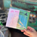 Someone holding the Wicked Inspired Pink Green Face Gem Set in front of a vintage teal Volkswagen bus.