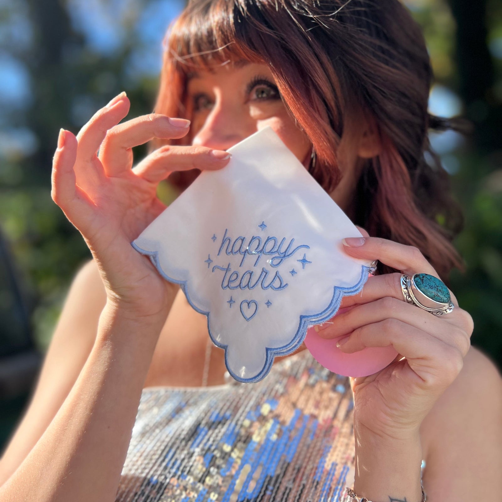 A woman holding the Happy Tears Embroidered Handkerchief in front of herself.