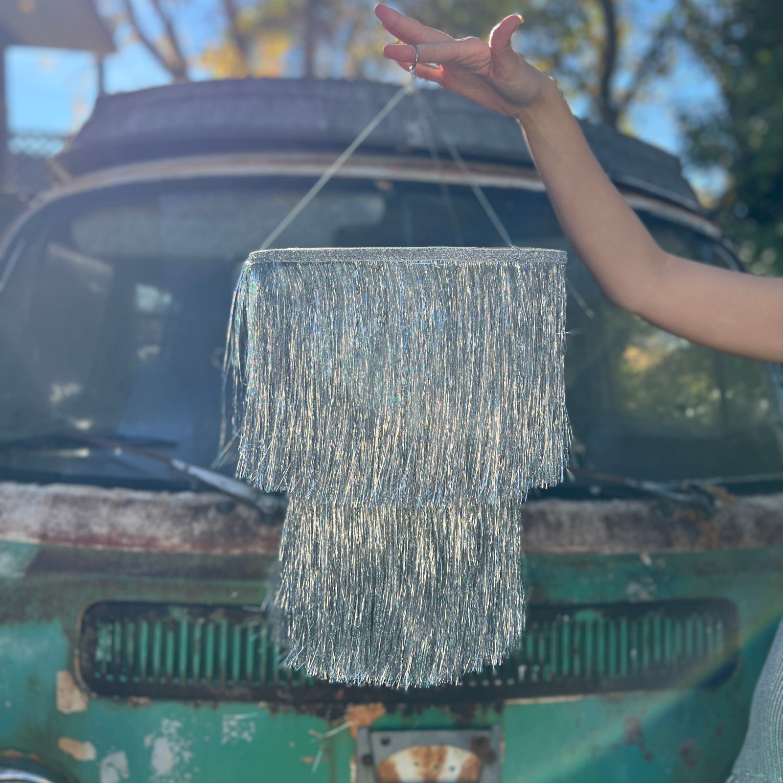 Someone holding the Disco Party Chandelier in front of a vintage teal Volkswagen bus.