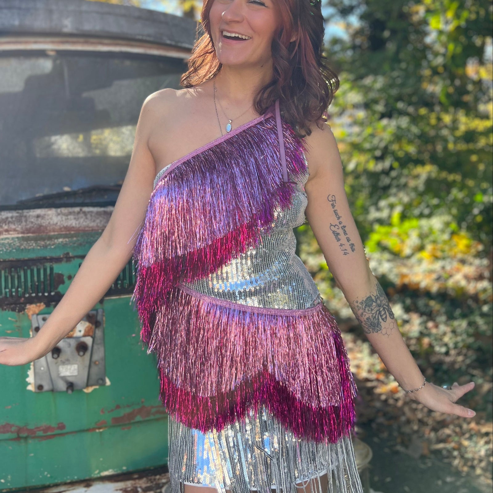 A woman wearing the Tickled Pink Scalloped Layered Fringe Banner in front of a vintage teal Volkswagen bus.