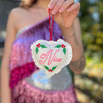 Someone holding the Naughty or Nice Christmas Cross Stitch Double Sided Heart Ornament showing off the nice side.