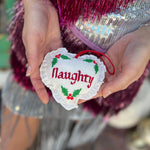 Someone holding the Naughty or Nice Christmas Cross Stitch Double Sided Heart Ornament showing off the nice side.