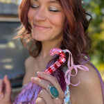 A woman holding the Disco Candy Cane Ornament close to her face.