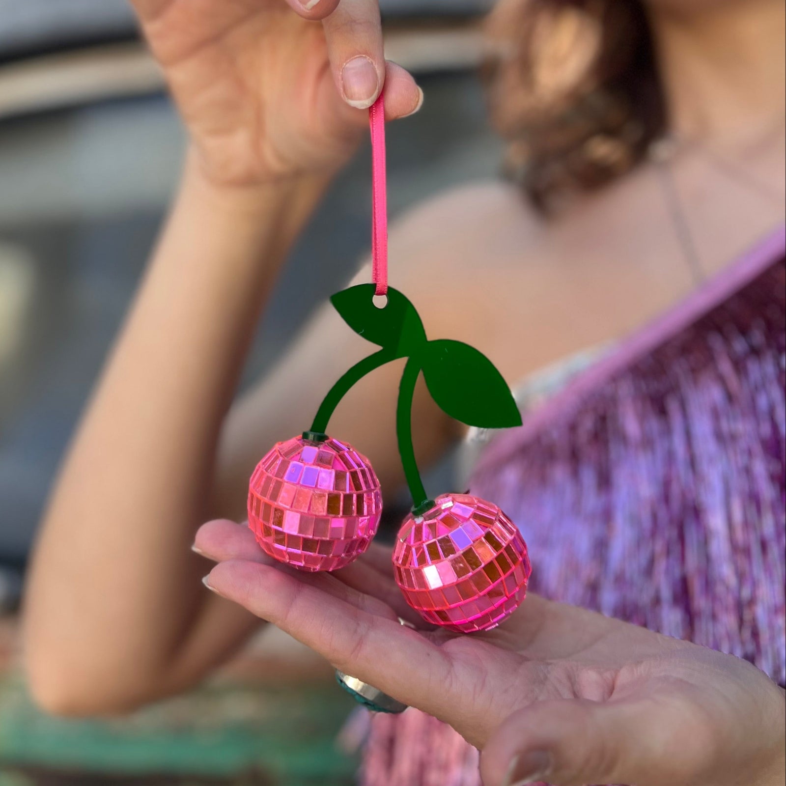 Someone holding the Disco Cherry Ornament in front of themselves.