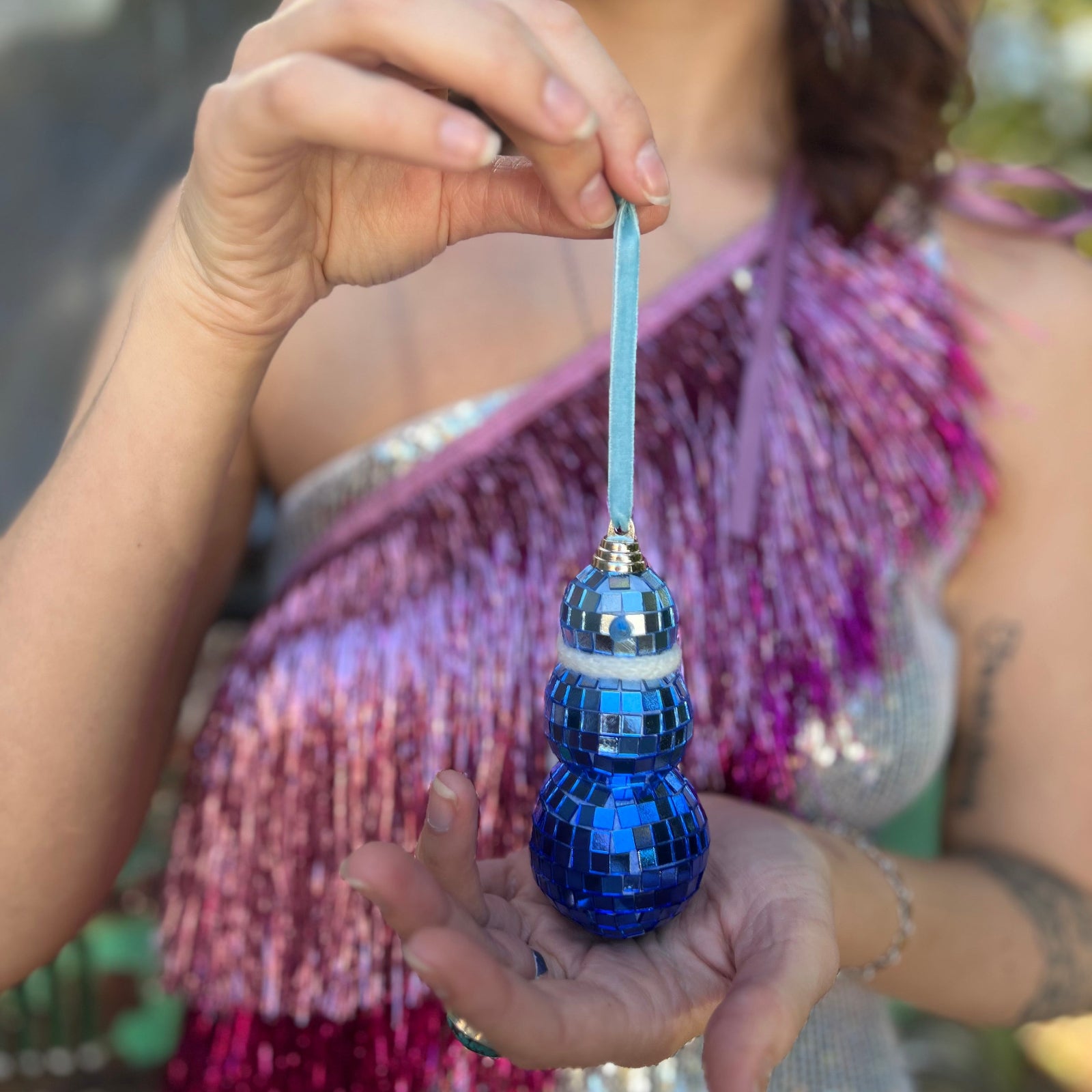 Someone holding the Disco Blue Snowman Ornament in front of themselves.