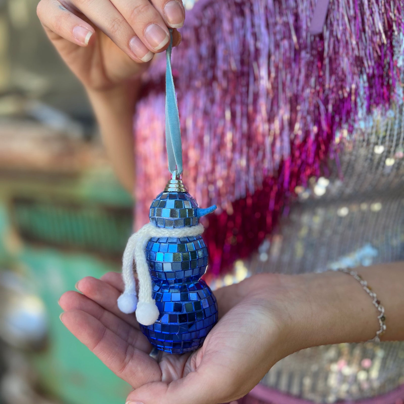 Someone holding the Disco Blue Snowman Ornament in front of themselves.
