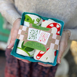 Someone holding the Happy Holidays Tea Towel Set of 2 in front of themselves.