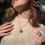 A woman wearing the Real Copper Acorn Necklace with a beige sweater.