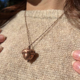 An up-close image of a woman wearing the Real Copper Acorn Necklace with a beige sweater.
