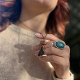 Someone wearing the Black Kyanite Crystal Copper Mushroom Necklace with a beige sweater.