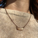 Someone wearing the Orange Kyanite Bar Crystal & Copper Necklace with a beige sweater.