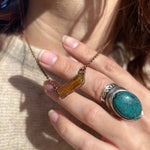 Someone wearing the Orange Kyanite Bar Crystal & Copper Necklace with a beige sweater.