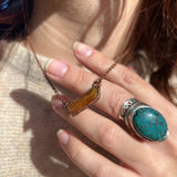 Someone wearing the Orange Kyanite Bar Crystal & Copper Necklace with a beige sweater.