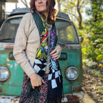 A woman wrapped up in the Cheshire Inspired Pashmina in front of a vintage teal Volkswagen bus.