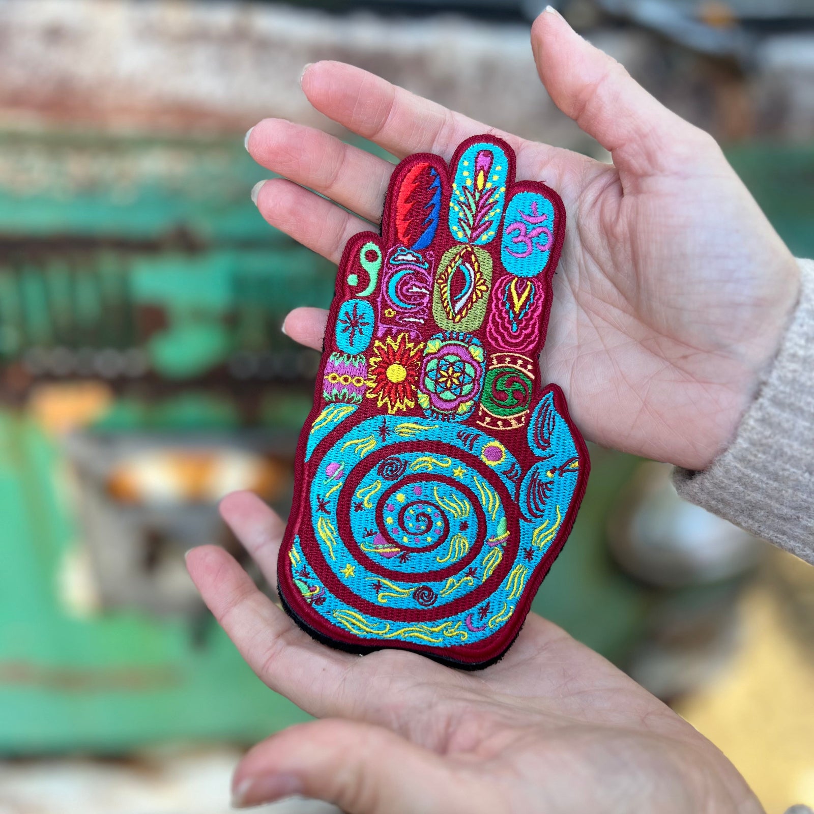 Someone holding the Palm Reader Iron-On Patch - Hippie Bohemian Embellishment in front of a vintage teal Volkswagen bus.