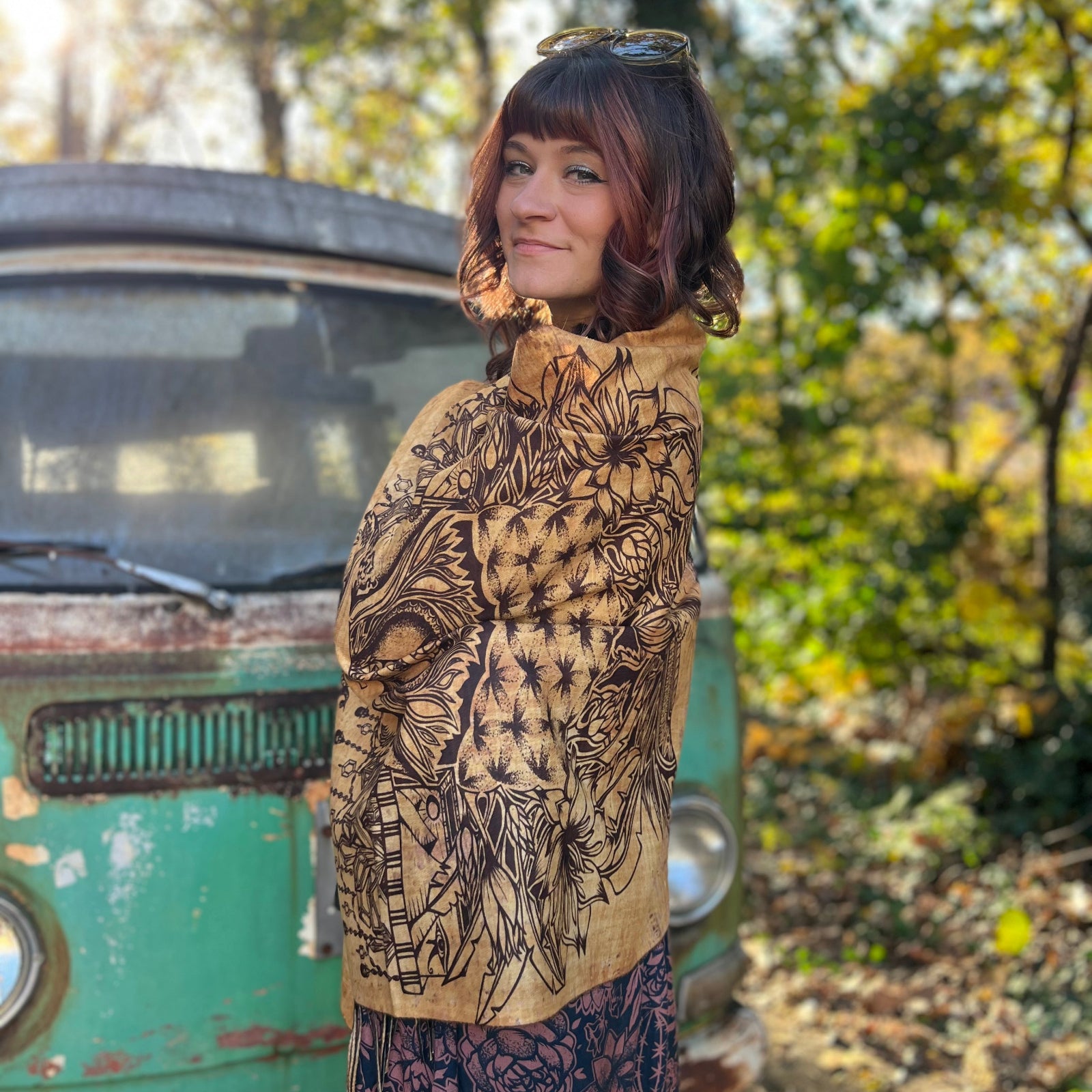 A woman wrapped up in the Cats Under The Stars Pashmina in front of a teal Volkswagen bus.