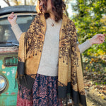 A woman wrapped up in the Cats Under The Stars Pashmina in front of a teal Volkswagen bus.