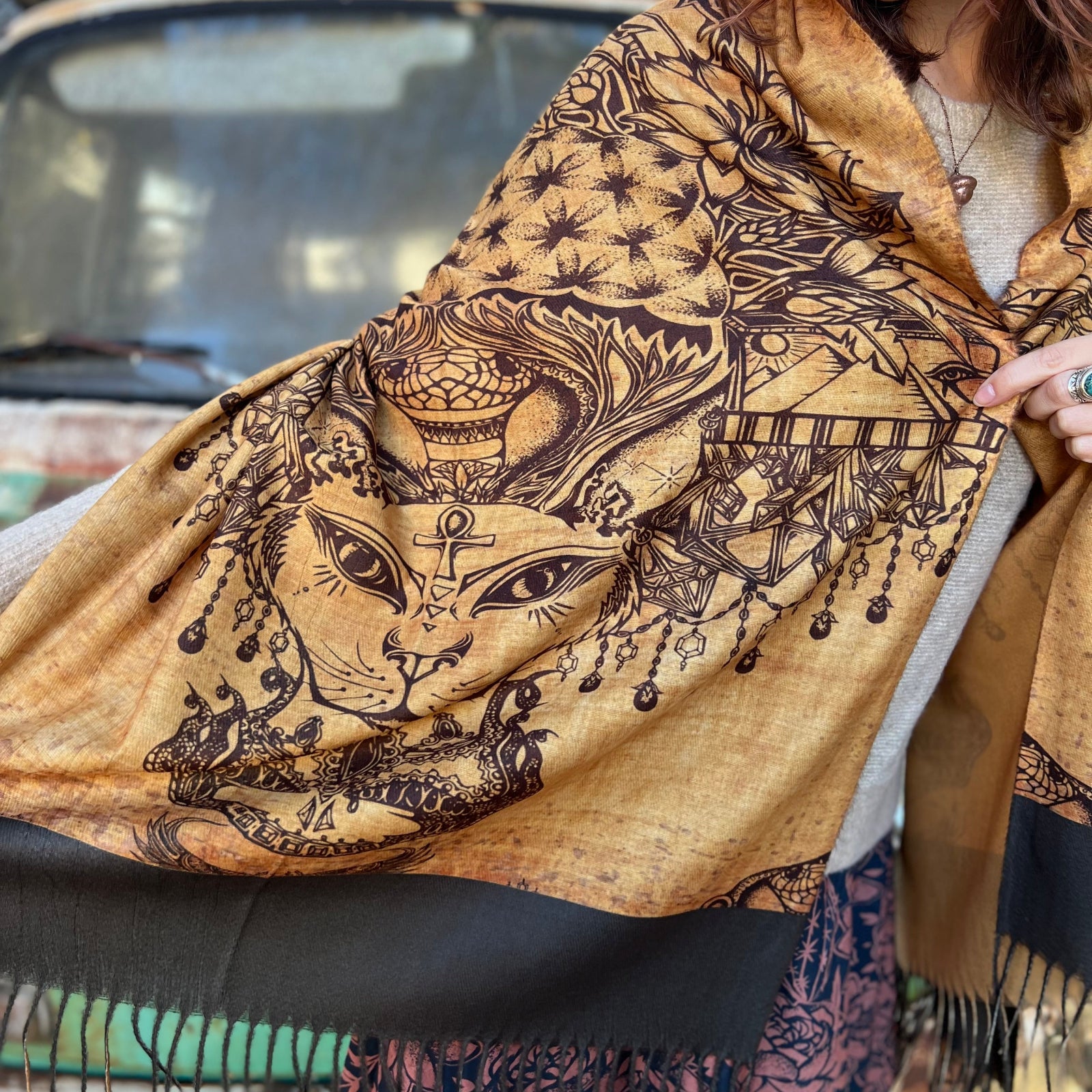 A woman wrapped up in the Cats Under The Stars Pashmina in front of a teal Volkswagen bus.
