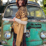 A woman wrapped up in the Cats Under The Stars Pashmina in front of a teal Volkswagen bus.